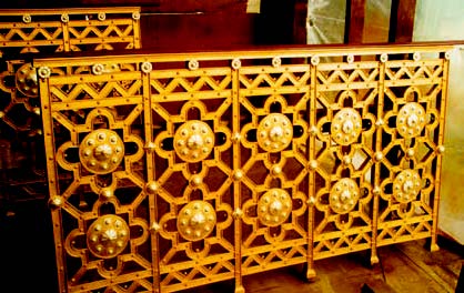 The varnish coating over the gilded, wrought-iron balustrades, kept in storage for over 30 years, had yellowed with age (top). After they were cleaned and the existing leaf and varnish barriers were sealed with shellac, other areas on the balustrades were sized and then gilded with 12-KT and 23.5-KT gold leaf.